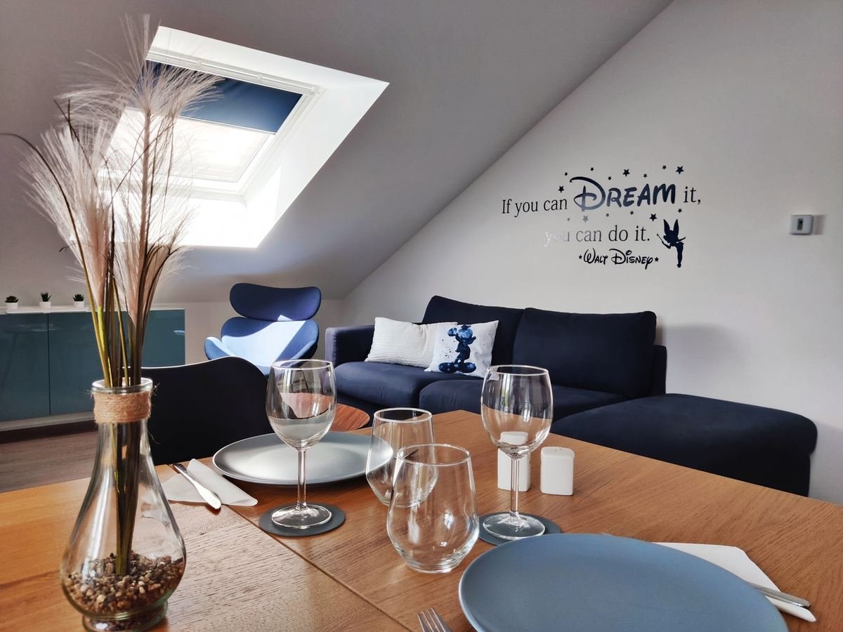 Coin repas dressé pour quatre, ouvert sur le canapé bleu marine du séjour