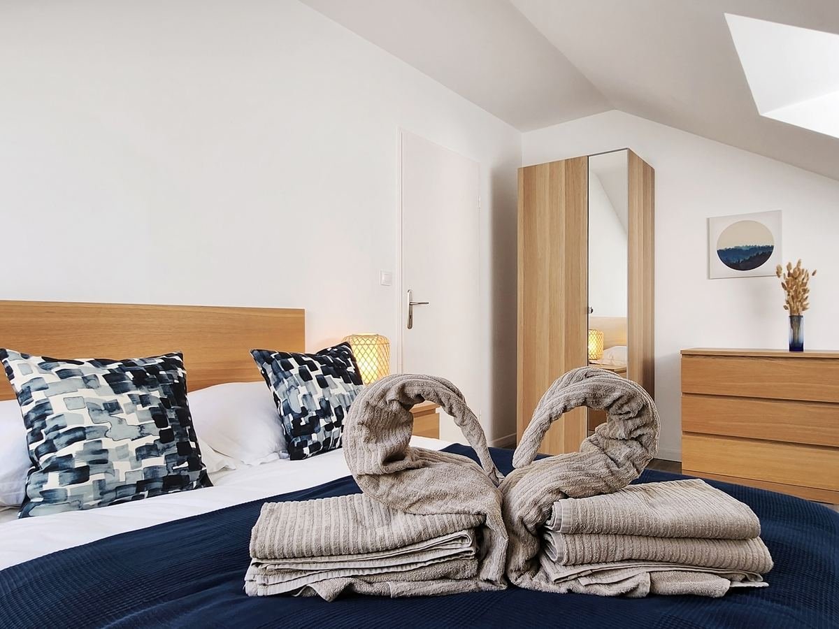 Lit double de la chambre avec serviettes de bain pliées, penderie et commode