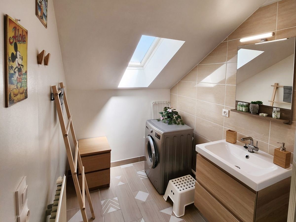 Salle d’eau aux tons bois avec lave-linge, meuble vasque et grand miroir