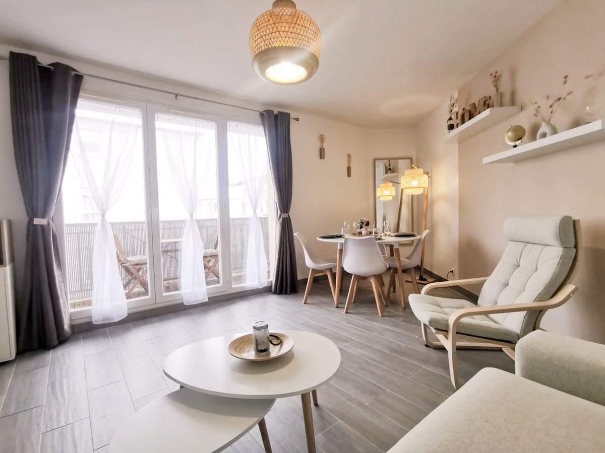 Séjour ouvert sur le balcon par une large porte-fenêtre, avec coin repas au fond